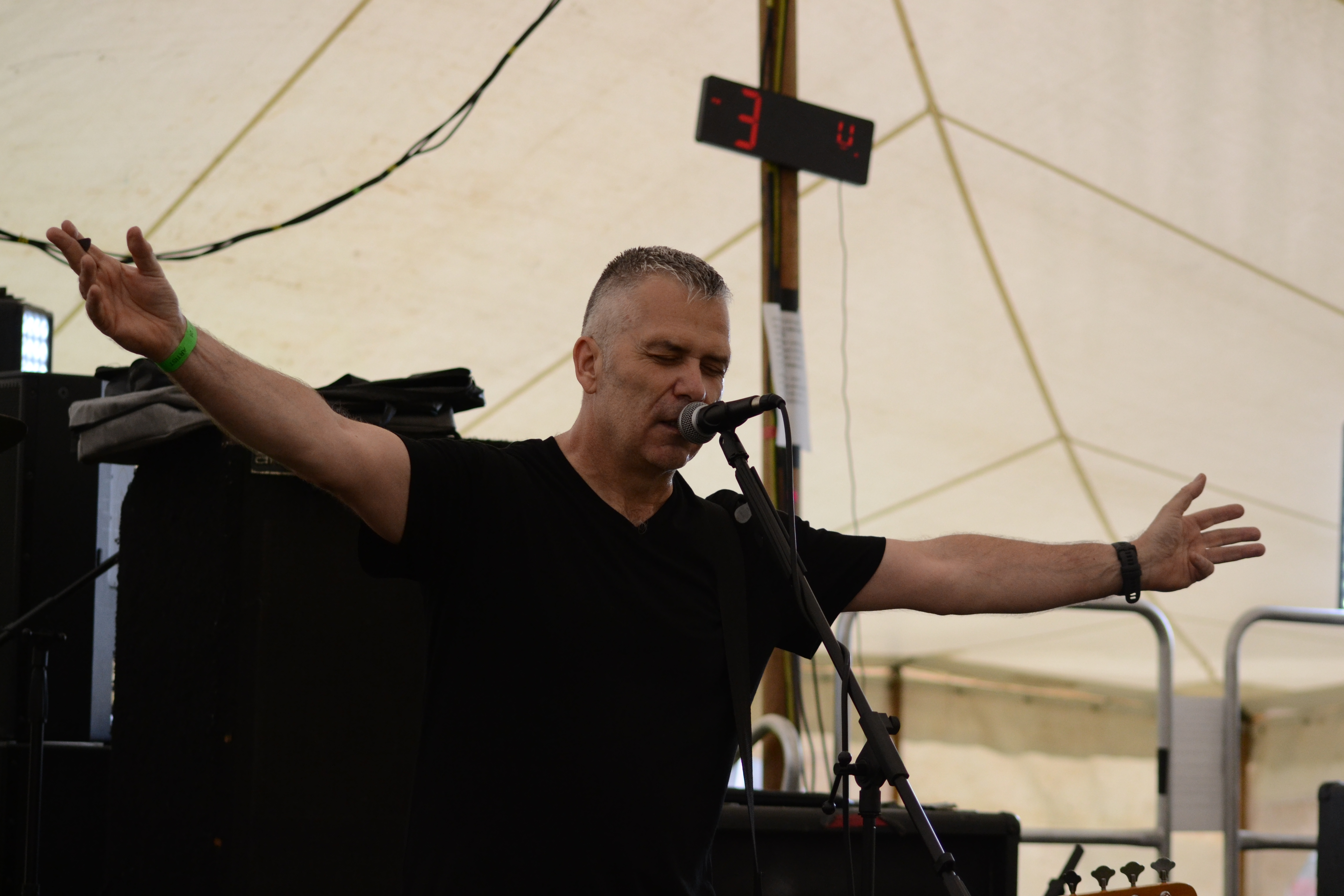 Bassist-vocalist shouting into the microphone with one hand raised to temple