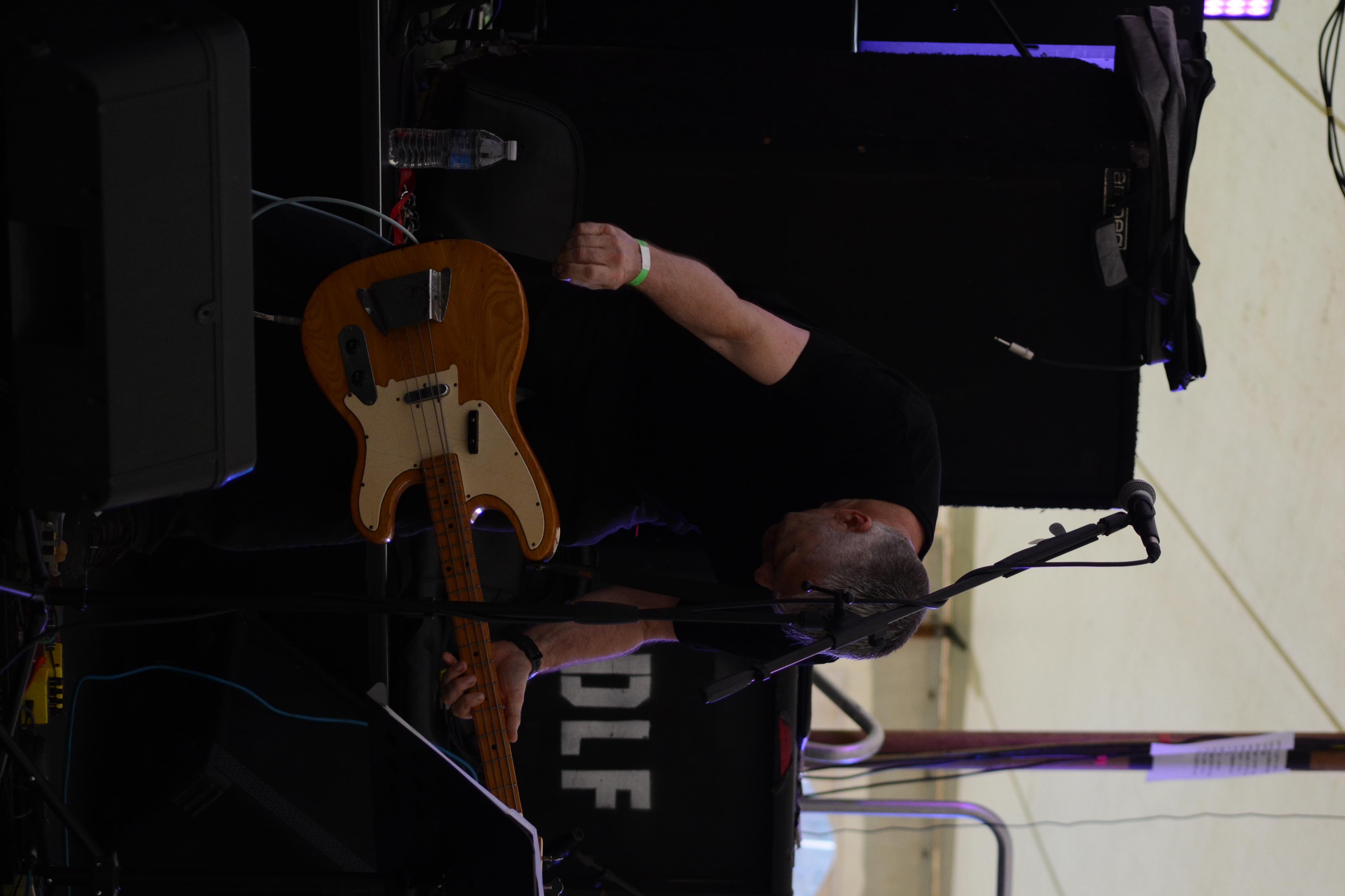 Guitarist-vocalist in cap and sunglasses gripping a handheld microphone with both hands