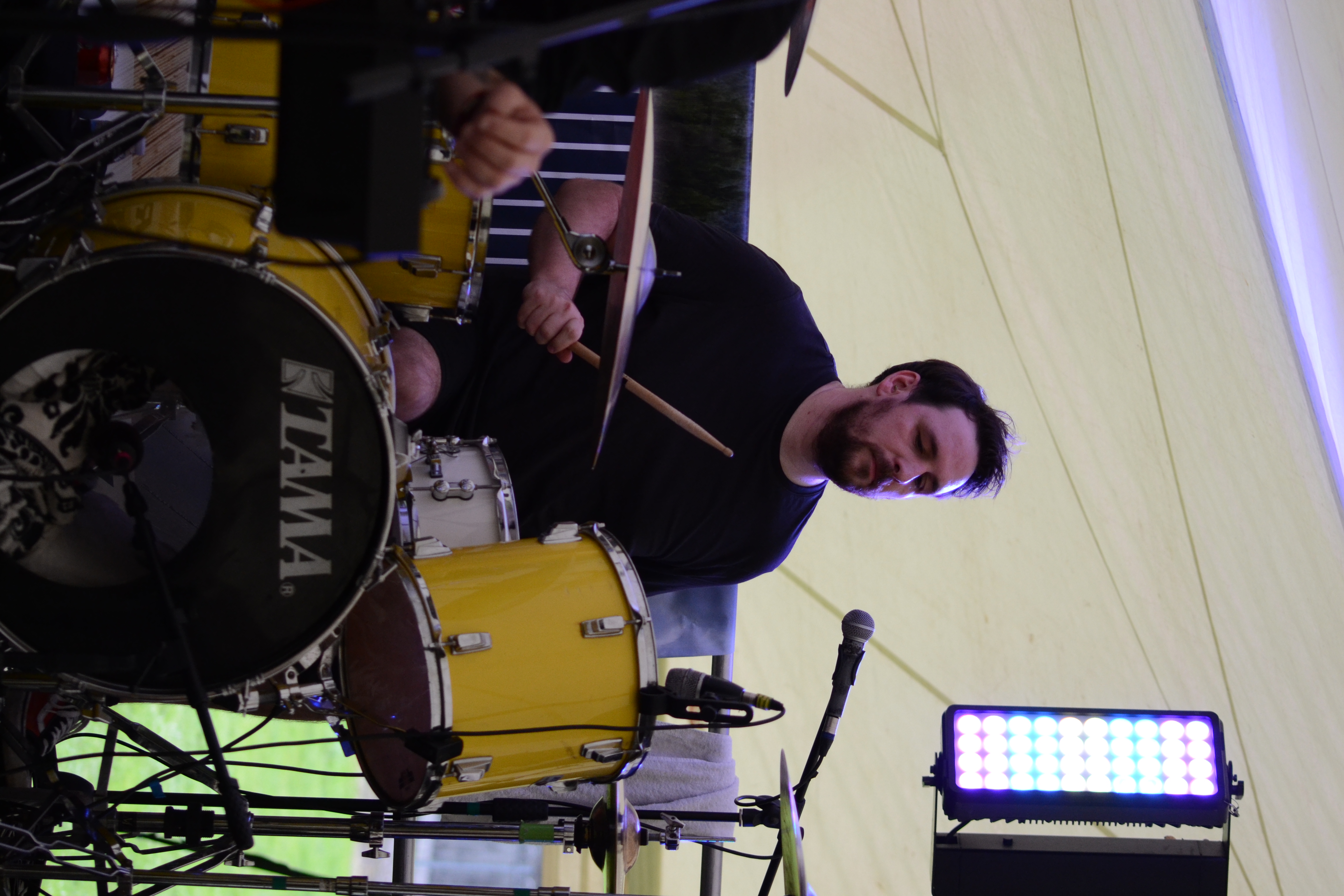 Drummer focused at the kit with red light panel glowing above
