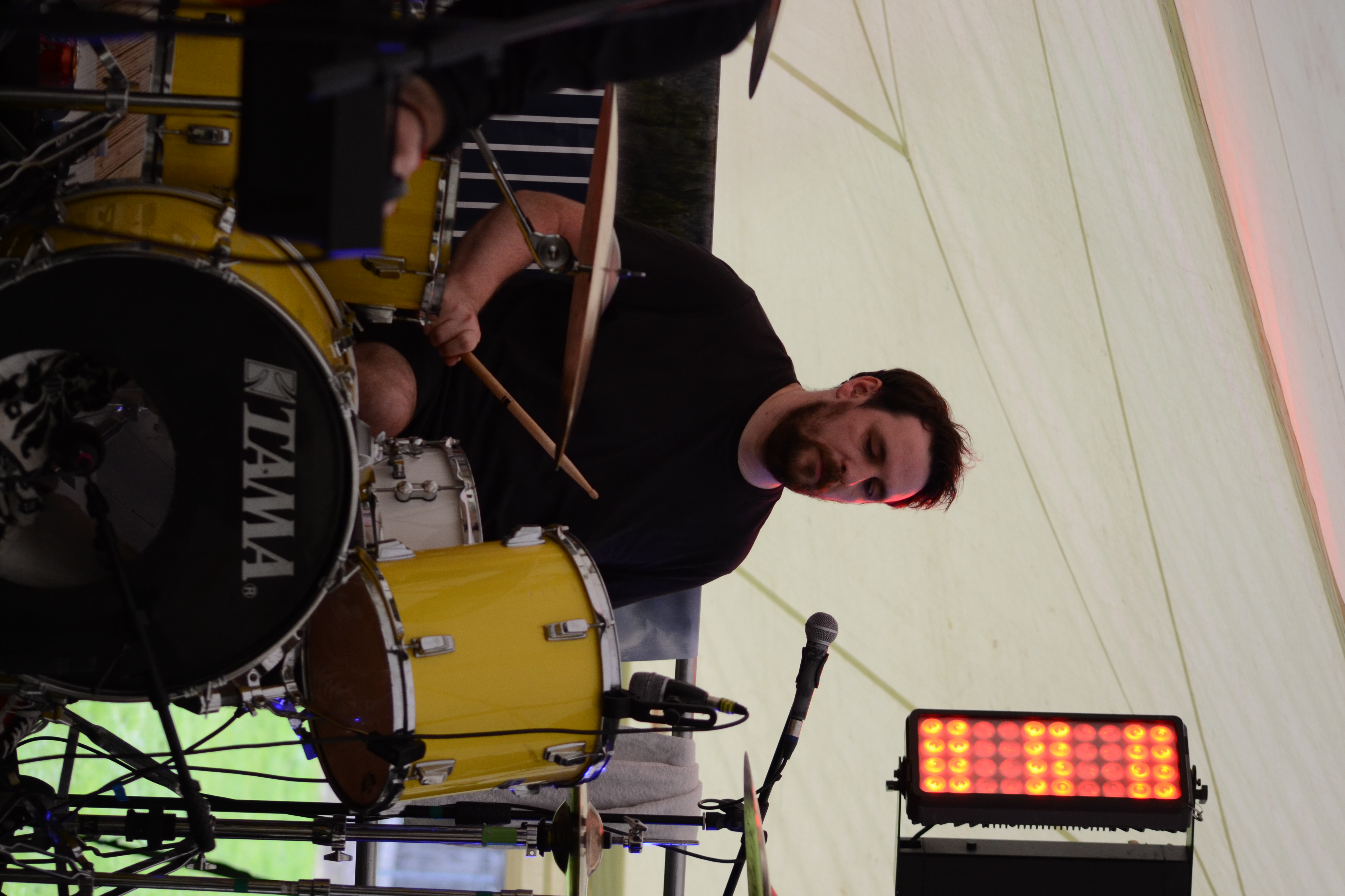 Guitarist-vocalist in cap and sunglasses singing into a handheld microphone