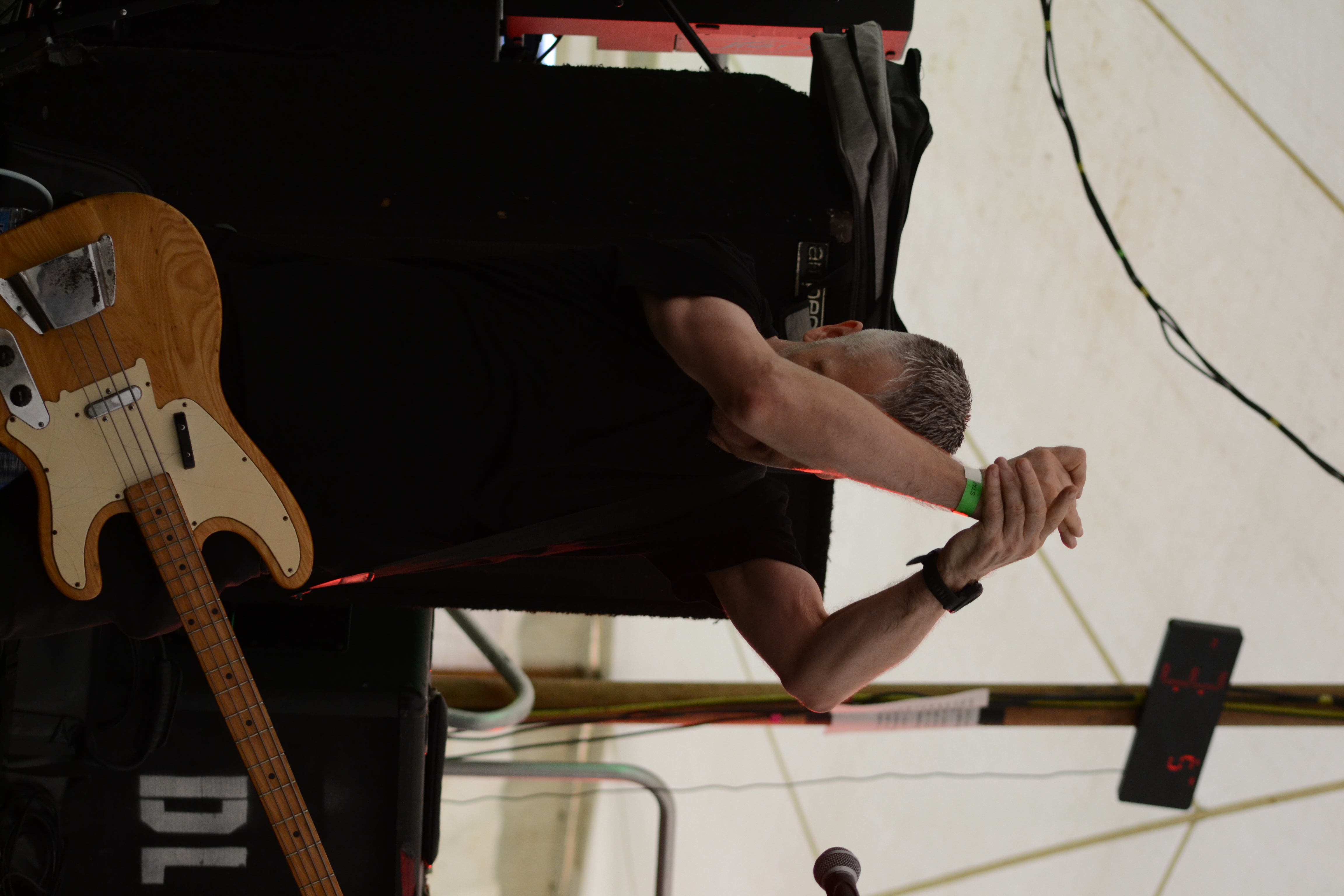Close-up of bassist-vocalist singing with drummer visible in the background