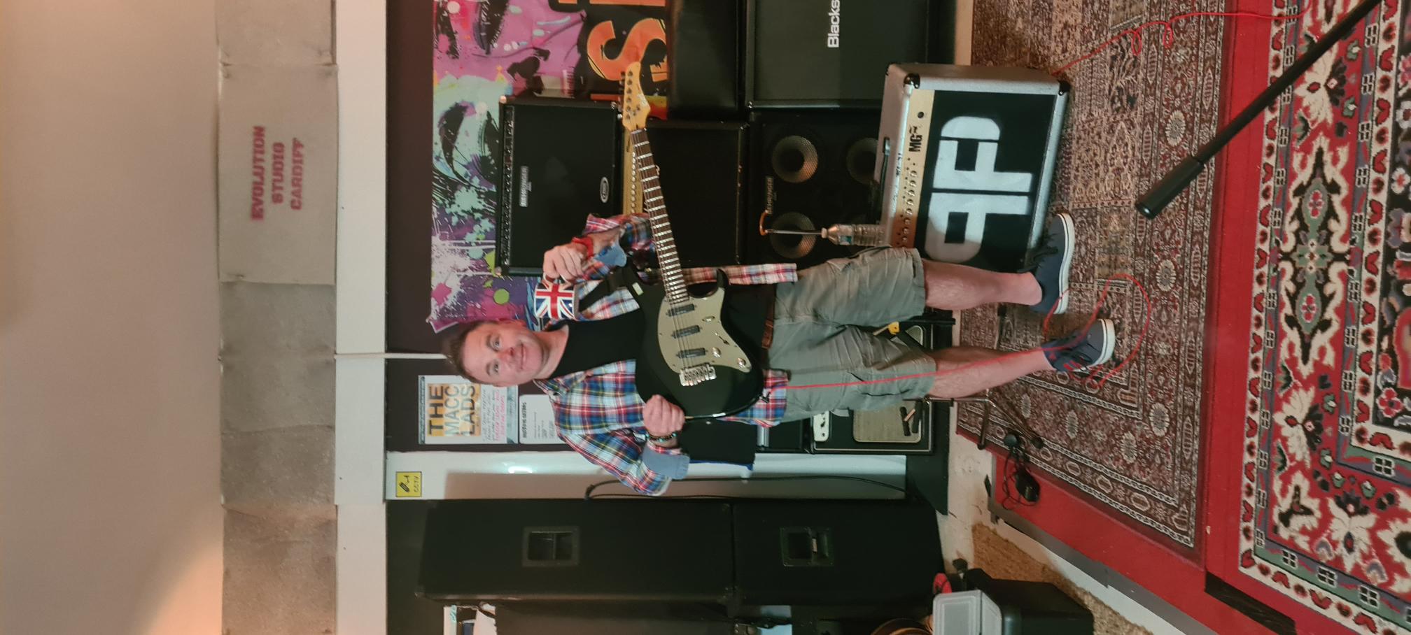 Guitarist holding an electric guitar and mug in Evolution Studio Cardiff