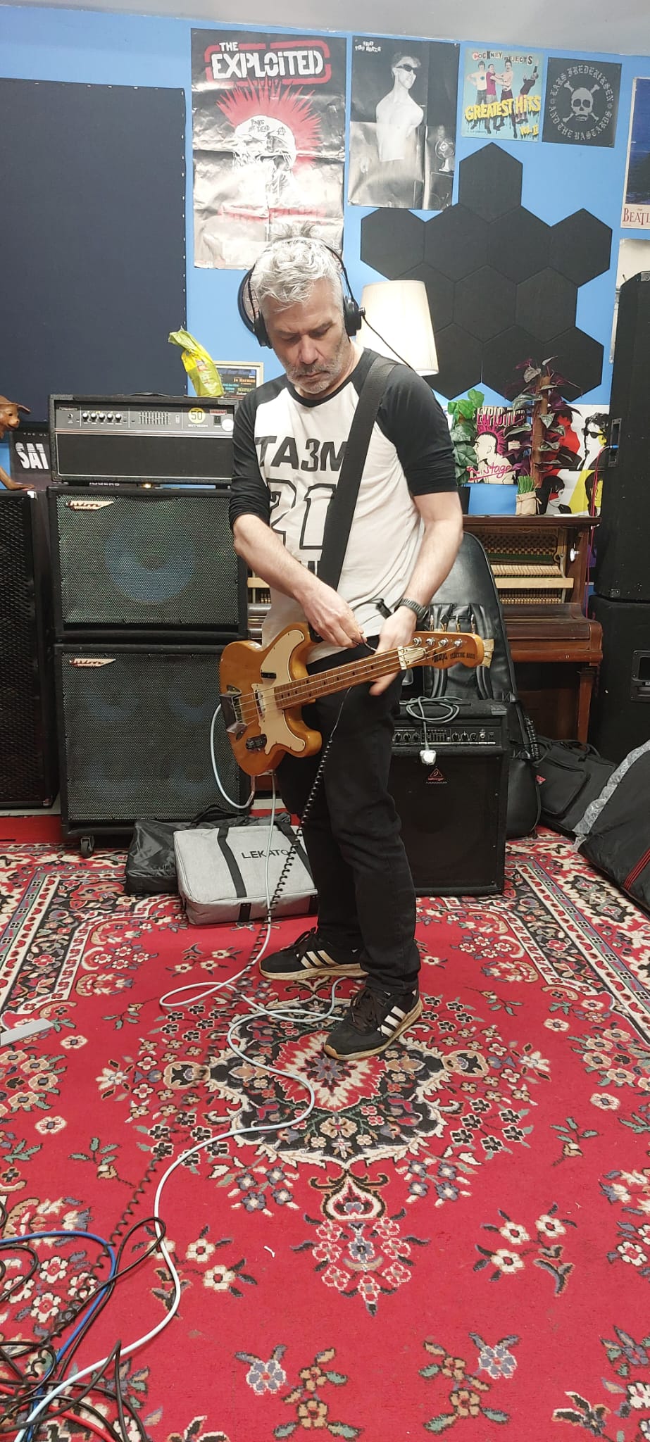 Bassist in headphones adjusting a cable on a vintage bass guitar
