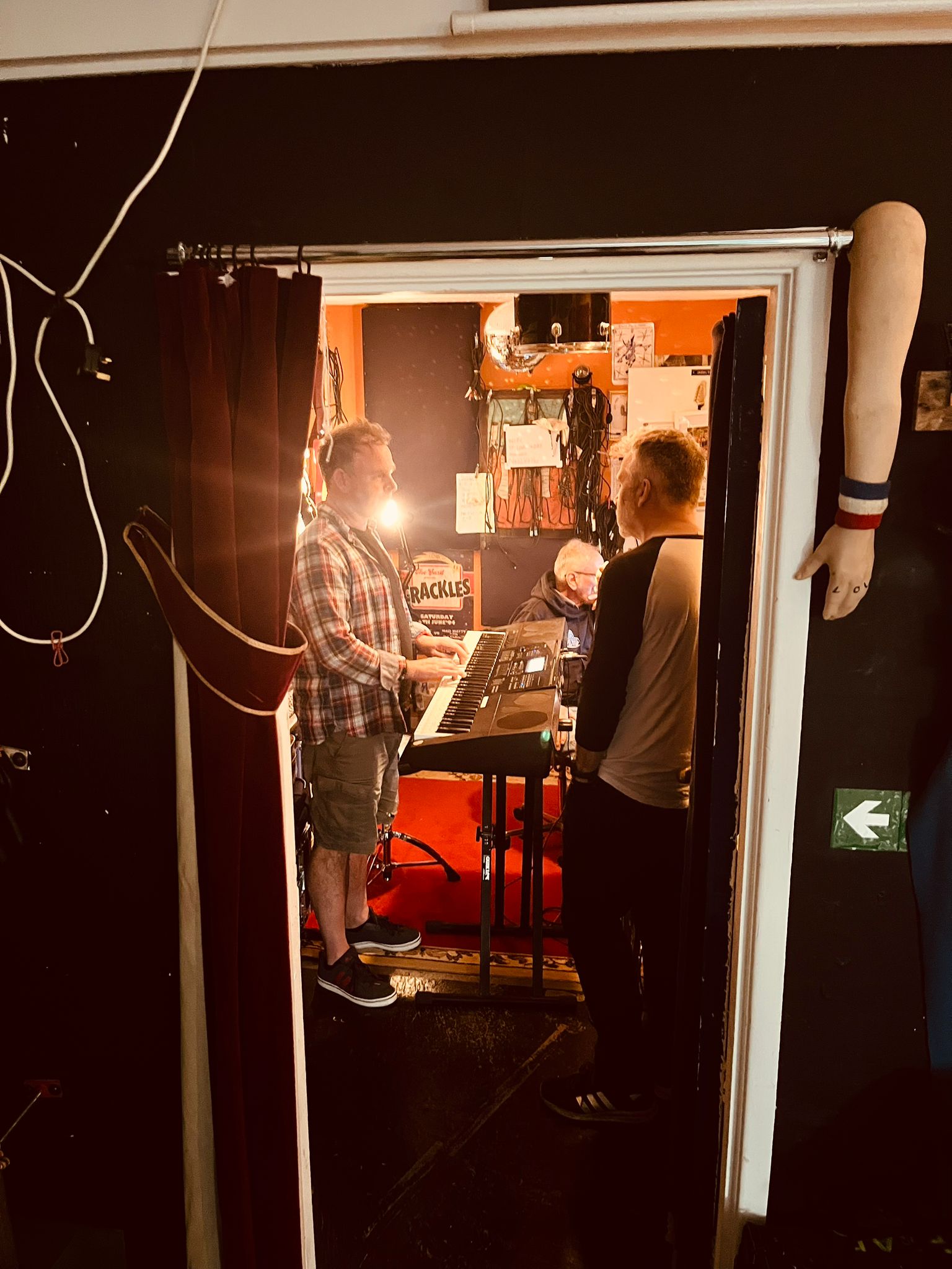 Doorway view into control room with two band members at a keyboard